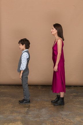 Woman in red dress and boy in grey suit vest in profile