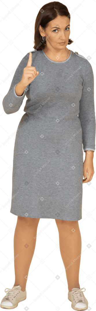 Vue de face d'une femme en robe grise pointant vers le haut avec un doigt
