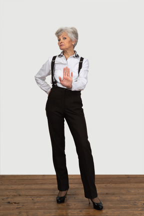 一位老不悦女性在办公室衣服显示停止手势的前视图