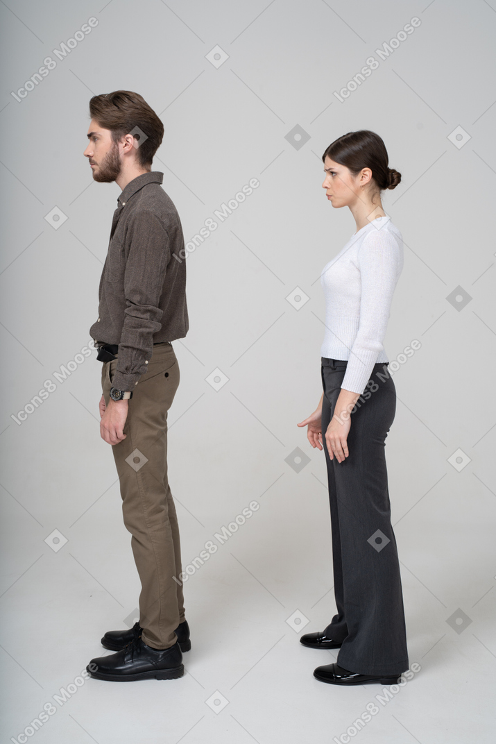 郁闷的年轻夫妇，在办公室服装站着不动的侧视图