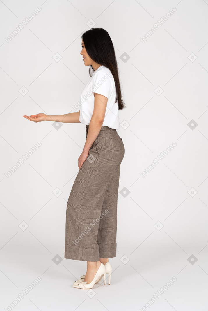 Vista lateral de uma jovem de calça e camiseta esticando a mão