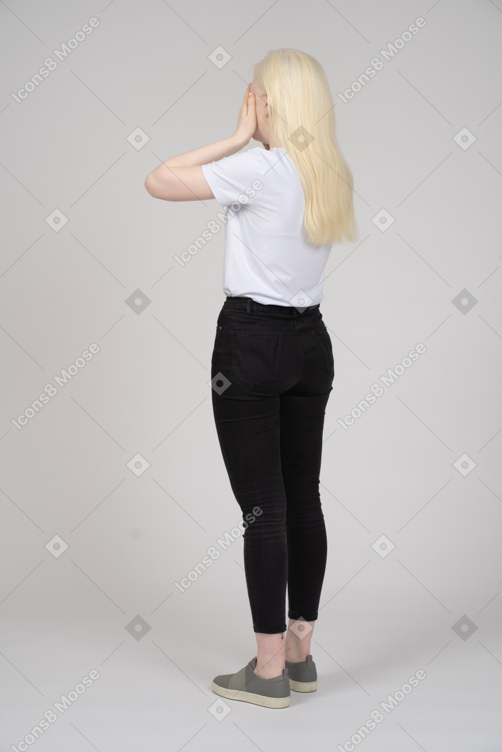 Back view of a woman covering her face