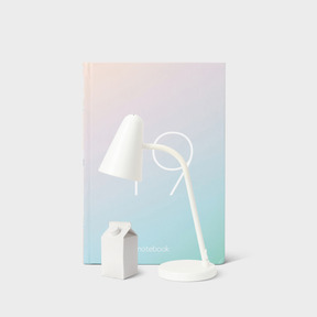 A white table lamp next to a box of milk