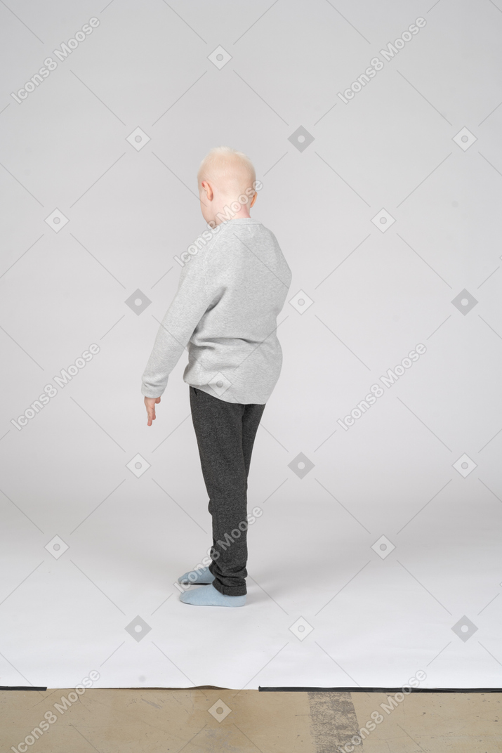 Three-quarter back view of a boy standing