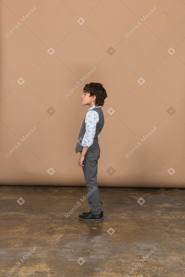프로필에 서 있는 회색 양복을 입은 소년