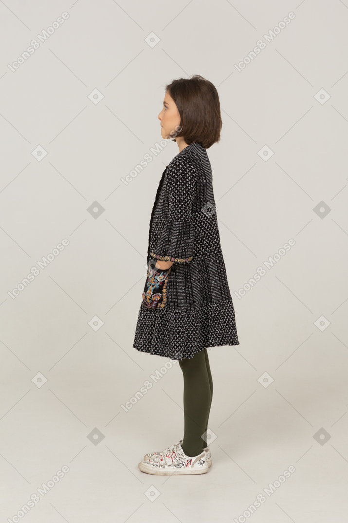Side view of a little girl in dress putting hands in pockets