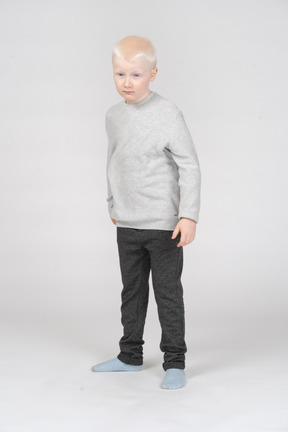 Vue de face d'un enfant garçon confiant à la recherche de côté tout en tricotant les sourcils