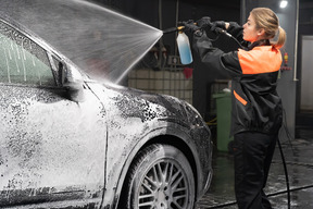 Junge frau, die auto wäscht