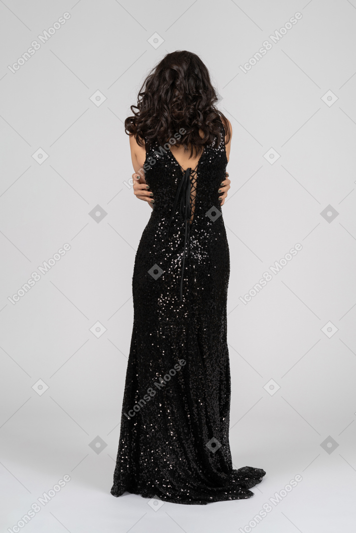 Woman in black evening dress hugging herself