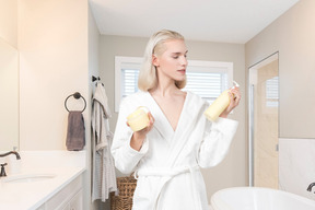 A woman in a bathrobe holding skin care products