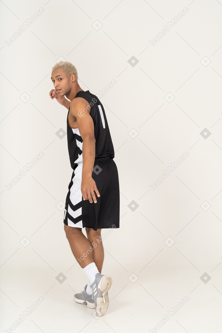 Vista posterior de tres cuartos de un joven jugador de baloncesto masculino alejándose
