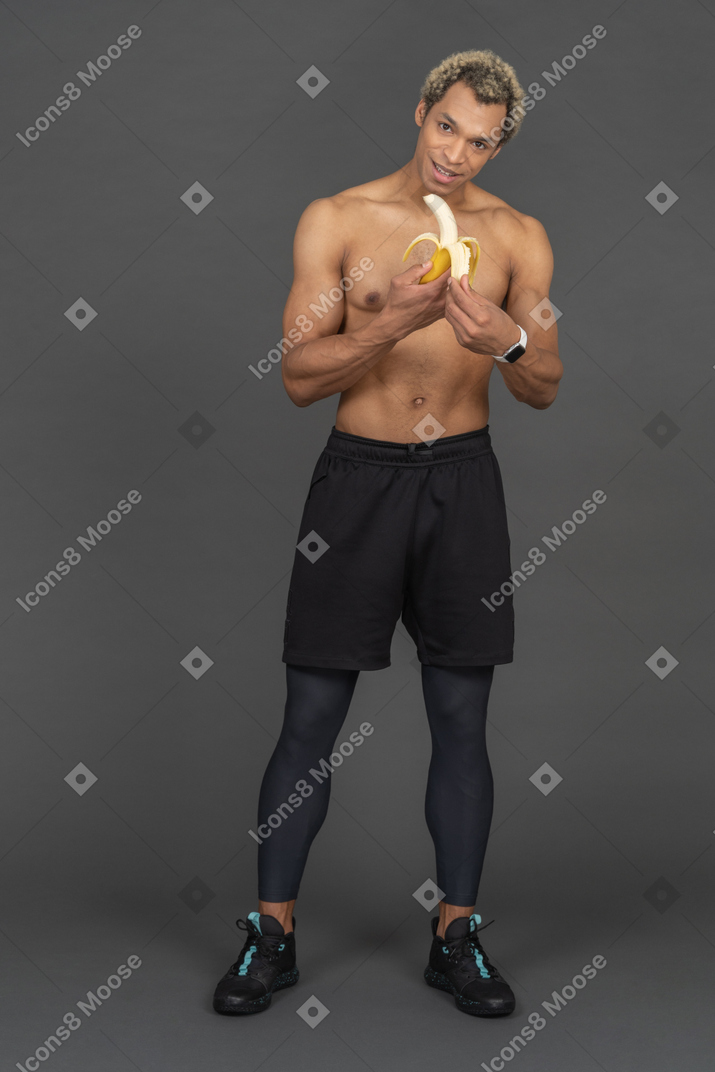 Uomo atletico che mangia una banana