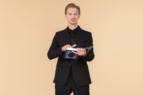 A white man in a fully black suit holding the quran