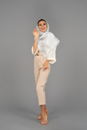 Cheerful young arab woman laughing and waving with a hand