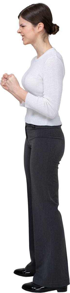 Vista lateral de uma mulher furiosa com roupas de escritório cerrando os punhos