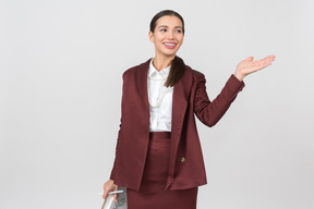 Attractive formally dressed woman with a clipboard pointing at something