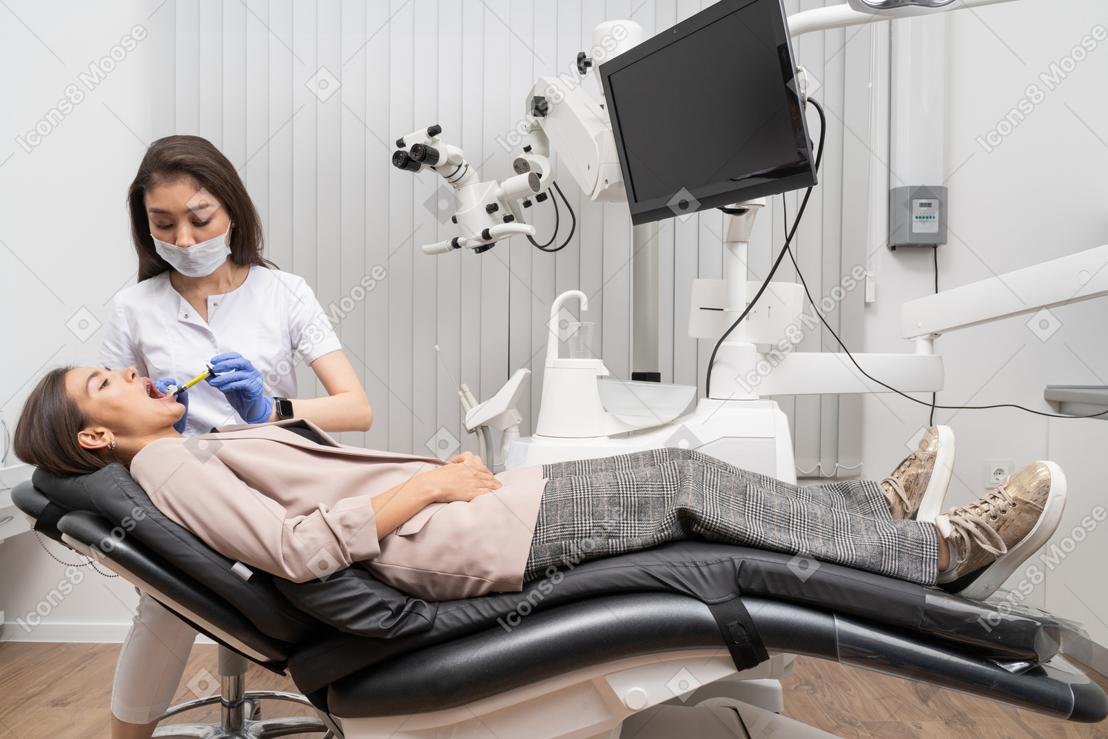 병원 캐비닛에서 그녀의 여성 환자에게 주사를하는 여성 치과 의사의 전체 길이