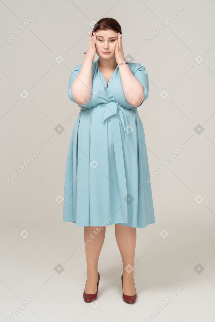 Vista frontal de uma mulher de vestido azul tocando a cabeça