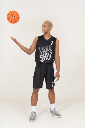 Three-quarter view of a young male basketball player throwing a ball