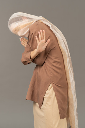 Frau mit schal auf dem kopf, der sich mit händen bedeckt, die stoppgeste zeigen