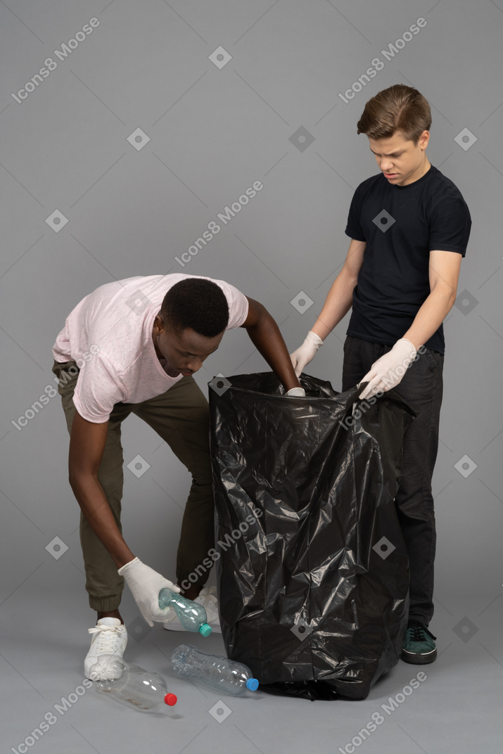 Young man collecting plastic bottles to put in a trash bag