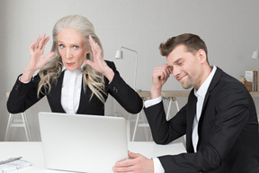 Man and sitting at laptop near disgruntled woman