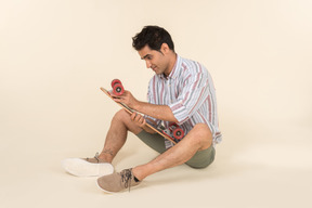 Young caucasian guy holding skate