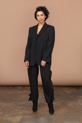 Vista frontal de uma mulher de negócios com uma careta em um terno preto, olhando para a câmera