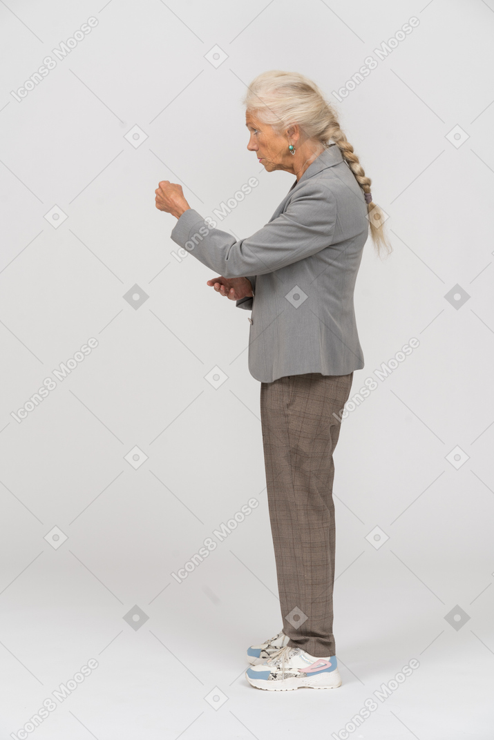 Vue latérale d'une vieille dame en costume montrant le poing