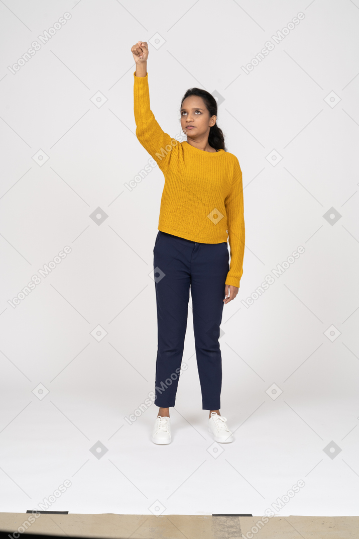 Front view of a girl in casual clothes standing with raised arm