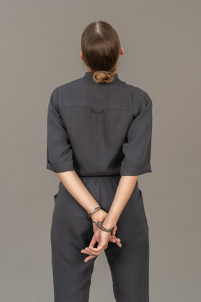 Back view of a young woman in a jumpsuit wearing handcuffs