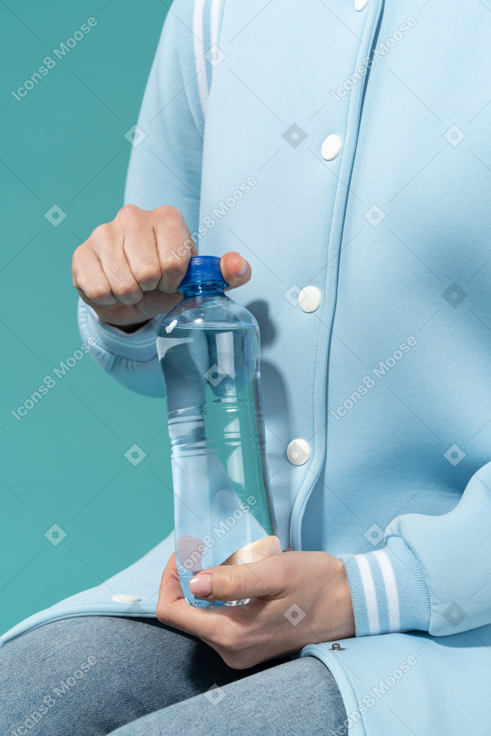 Frau öffnet eine flasche wasser