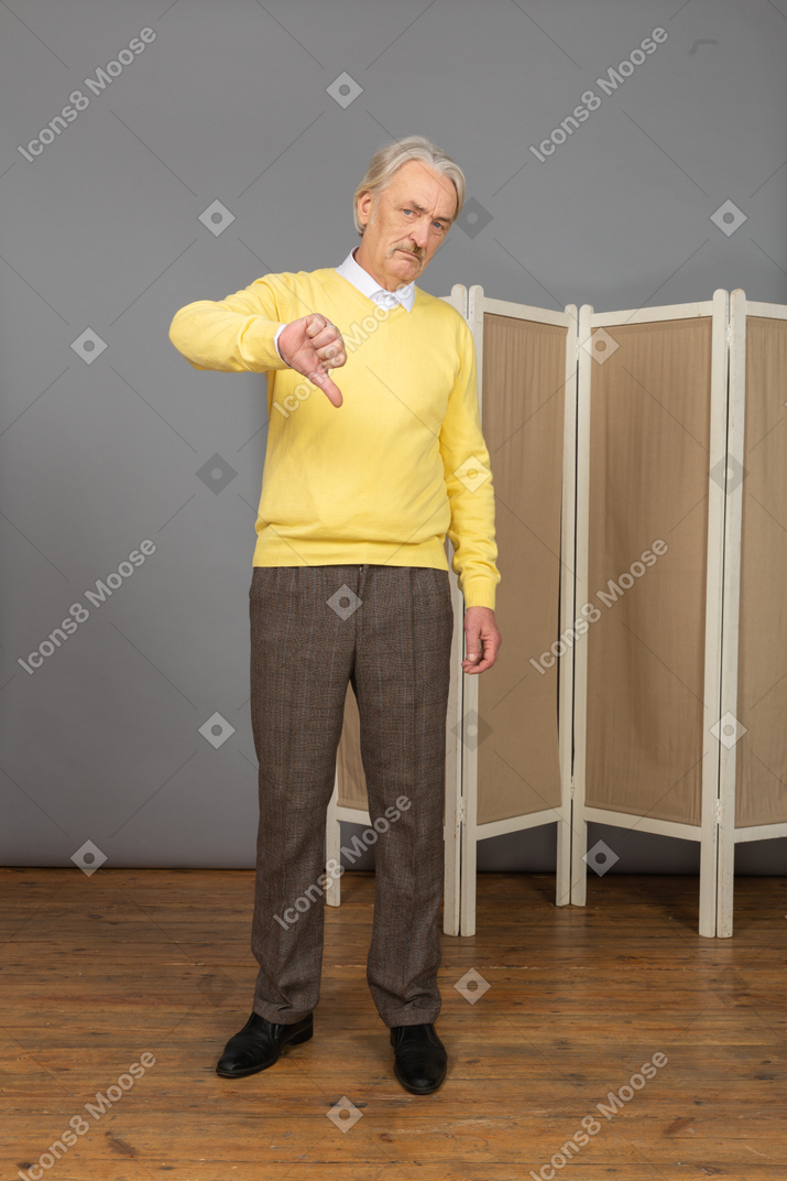 Front view of an old displeased man putting thumb down