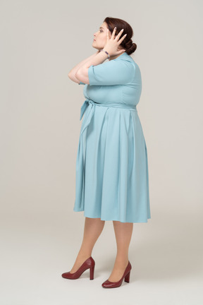 一个穿着蓝色连衣裙的女人用手捂住耳朵的侧视图