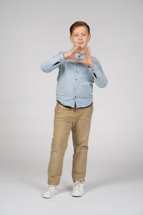 Front view of a boy making heart with fingers and looking at camera