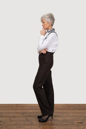 Side view of a thoughtful old lady in office clothing touching face