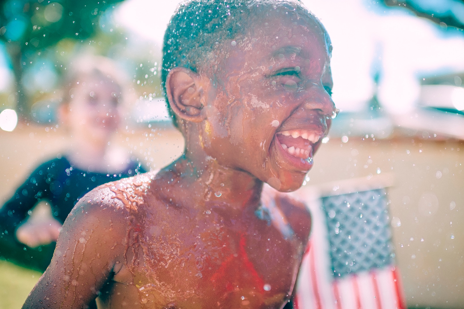 Lachendes kind mit amerikanischer flagge im hintergrund
