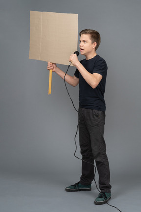 Young man speaking into a microphone and holding a poster