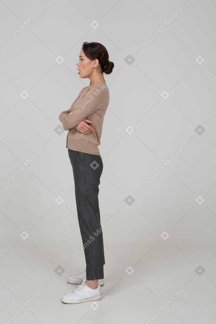 Vista laterale di una giovane donna stupita in maglione beige attraversando le mani