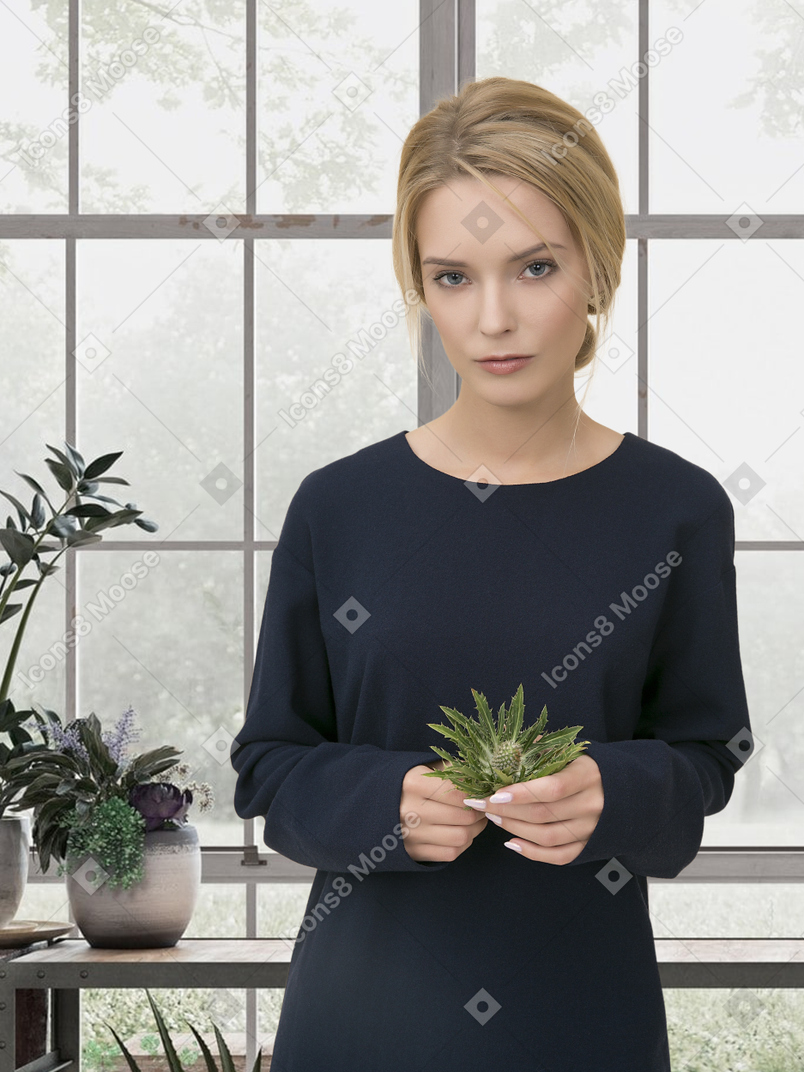 A woman holding a plant in a greenshouse