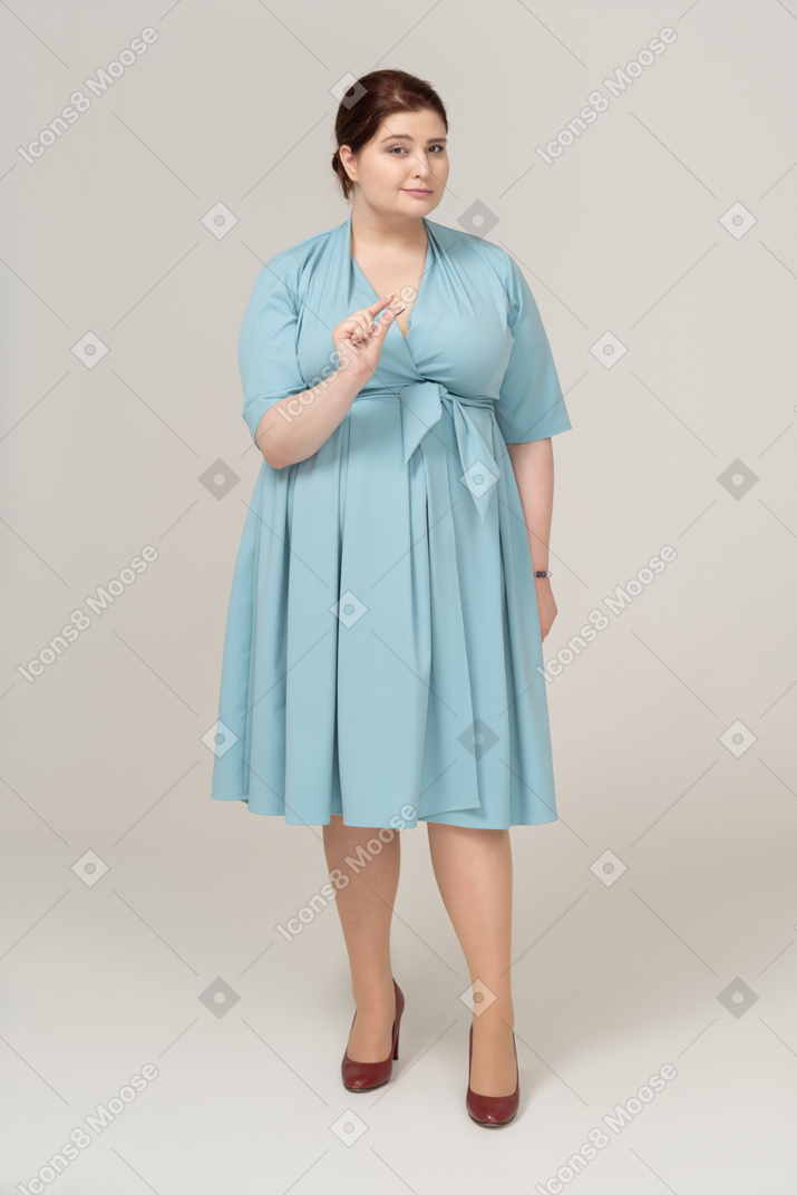 작은 크기의 무언가를 보여주는 파란 드레스를 입은 여성의 전면 모습