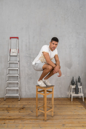 Homme avec les coudes sur les genoux accroupi sur une chaise