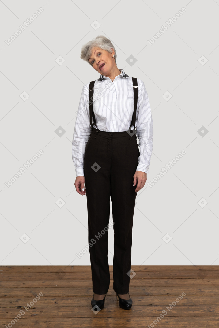 Front view of an old grimacing female in office clothes  touching head to shoulder