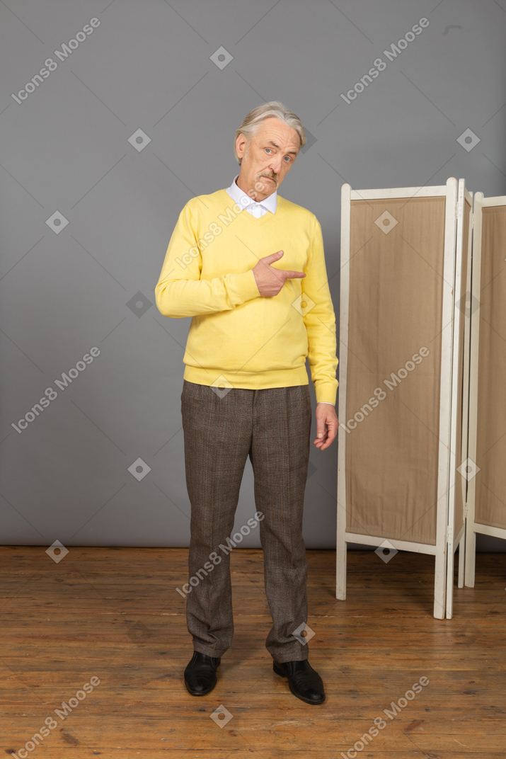 Front view of a questioning old man raising hand while looking aside
