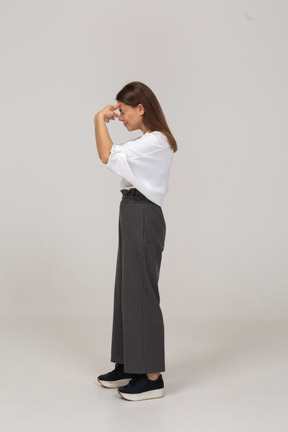 Side view of a young lady in office clothing touching head
