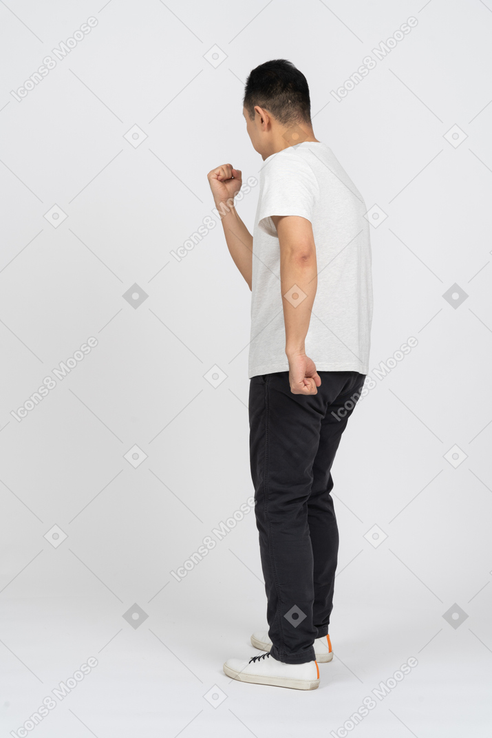 Rear view of a man in casual clothes threatening someone with fist
