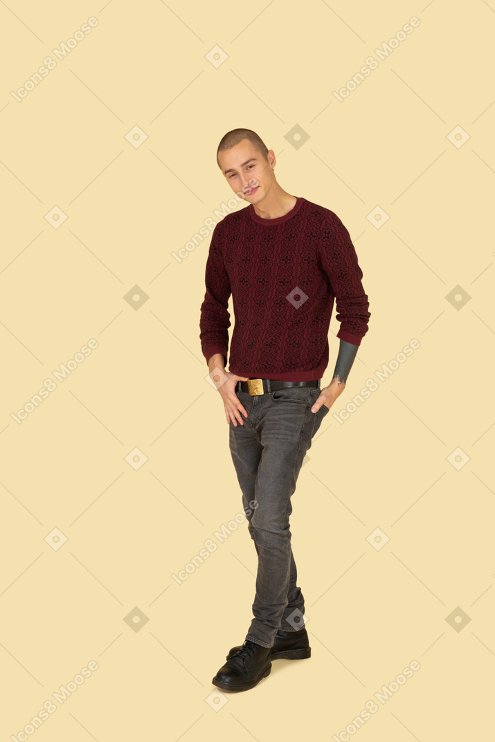 Front view of a walking young man in red pullover putting hand in pocket