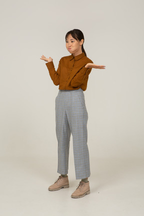 Side view of a funny young asian female in breeches and blouse raising hands