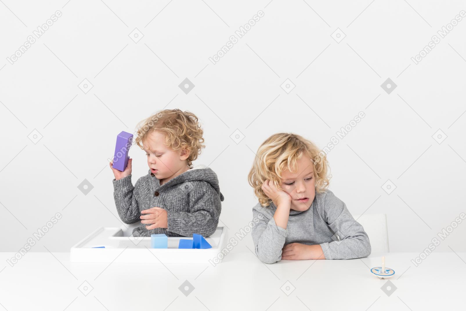 Baby boy jugando con cubos y su hermano mirando aburrido