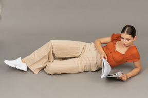 Young woman lying down with book